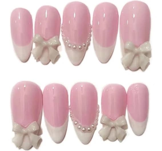 Soft pink French tip press-on nails with pearl accents and bow charms