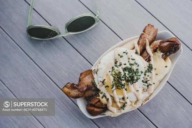 Gourmet hot dog with fried egg, bacon, and sauce. - SuperStock