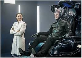 Neil Sandilands 8 inch x 10 inch Photograph The Flash (TV Series 2014 -) Seated in Chair w/Head Attached to Wires & Kim Engelbrecht Standing w/Arms Crossed kn at Amazon's Entertainment Collectibles Store