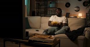 Smiling Bearded Man Sitting on Couch Watching TV and Eating Chips at Home Student Relaxes After, Stock Footage